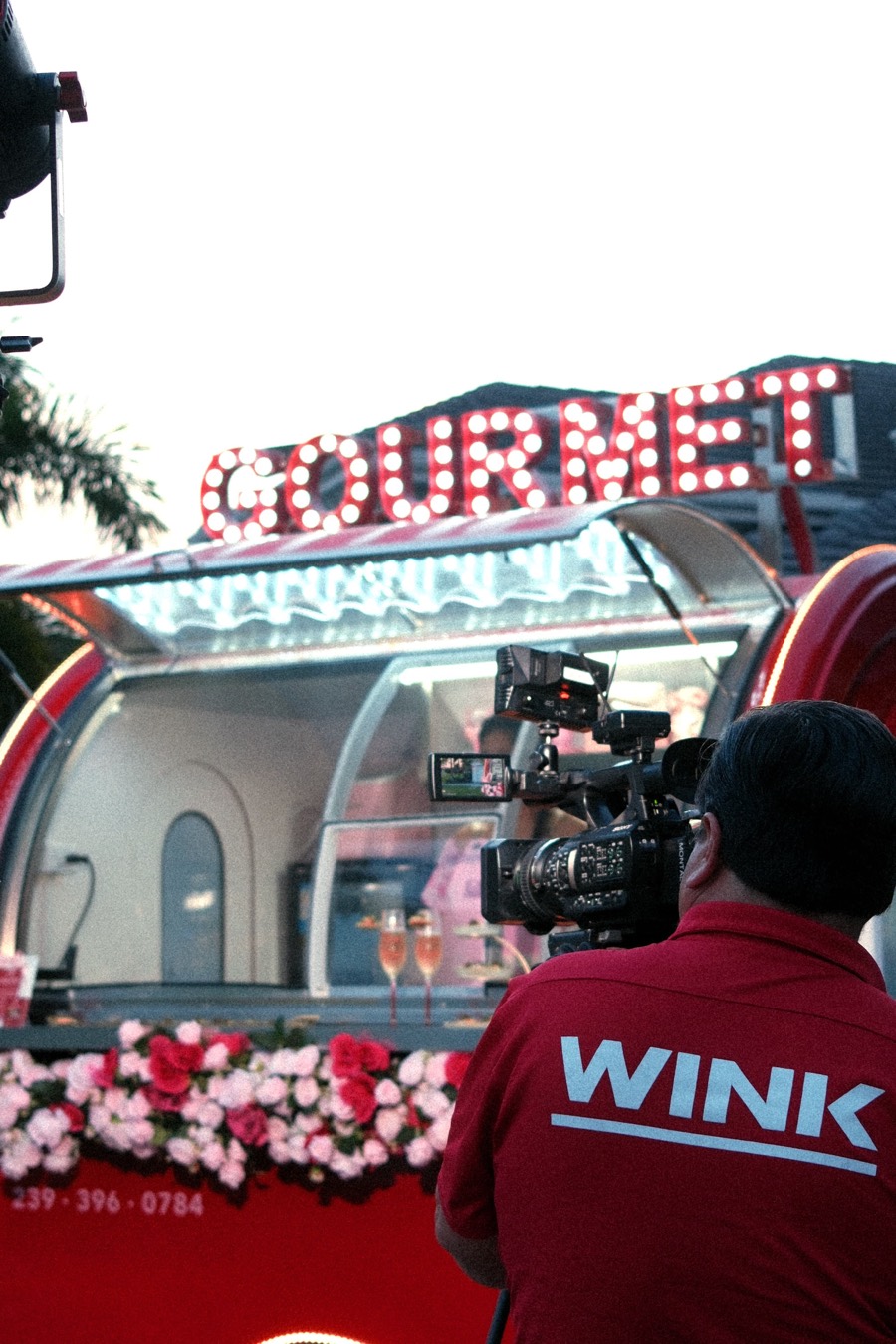 A WINK News camera operator filming the lit Chariot at dusk